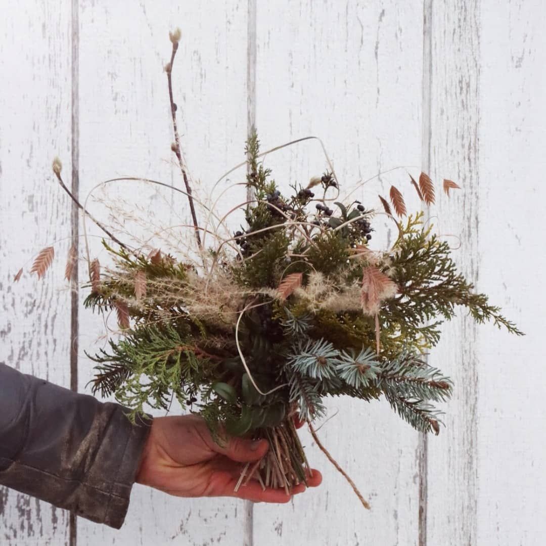 A person is holding a bouquet of flowers in front of a white wooden wall