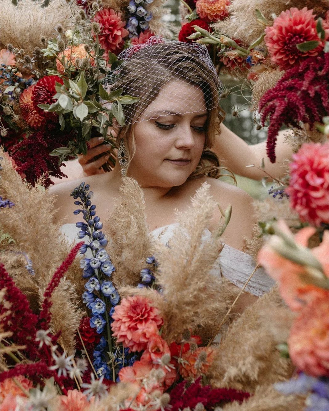 A woman in a wedding dress is surrounded by flowers.