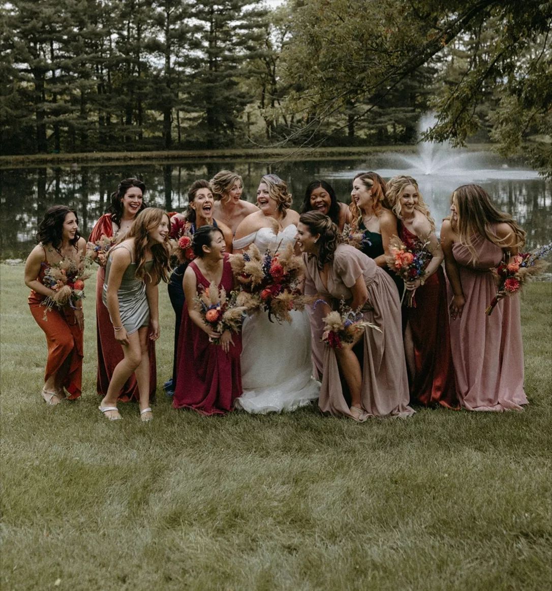 A bride and her bridesmaids are posing for a picture in front of a fountain.