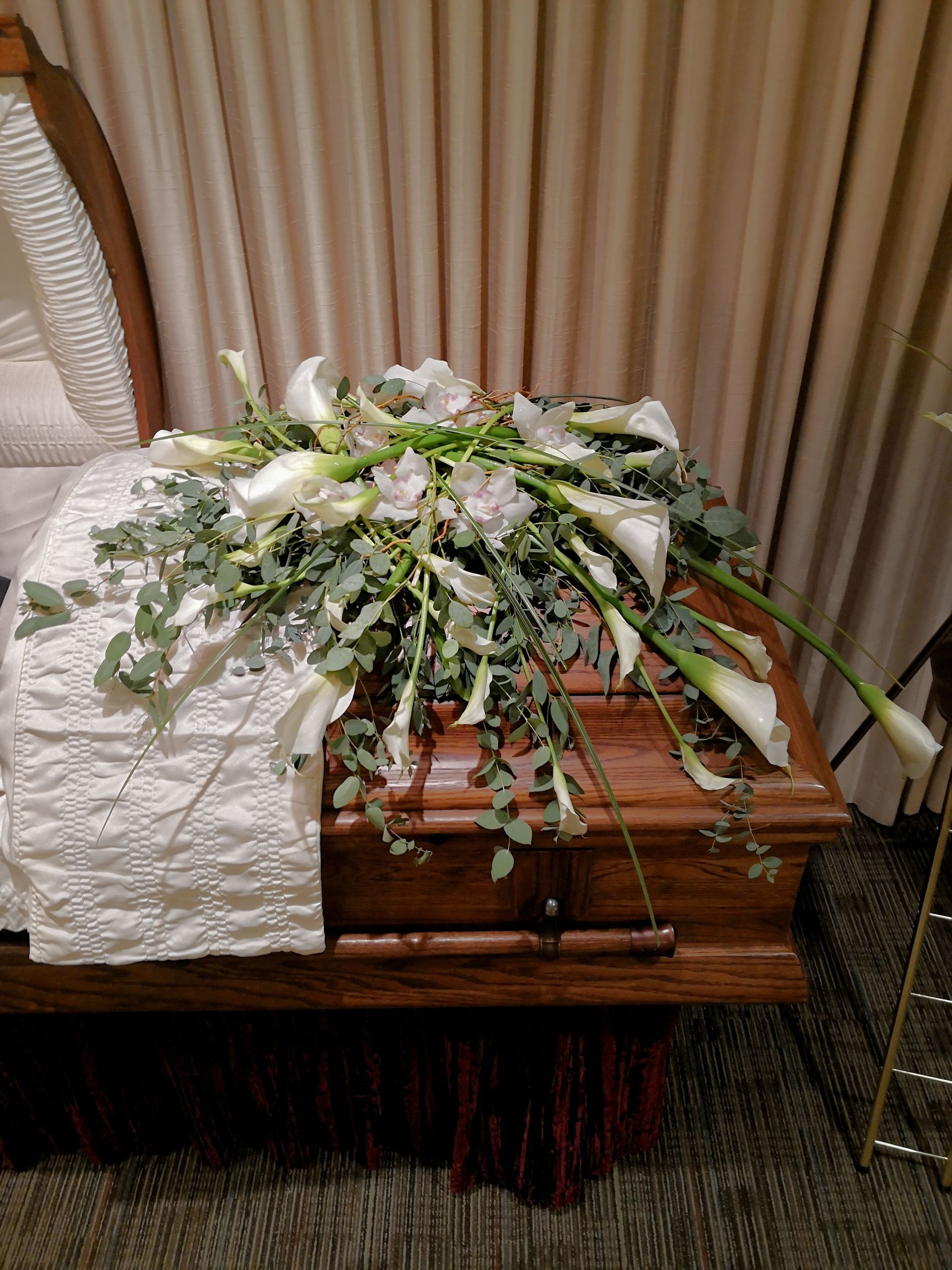 A coffin with flowers on top of it in a room.