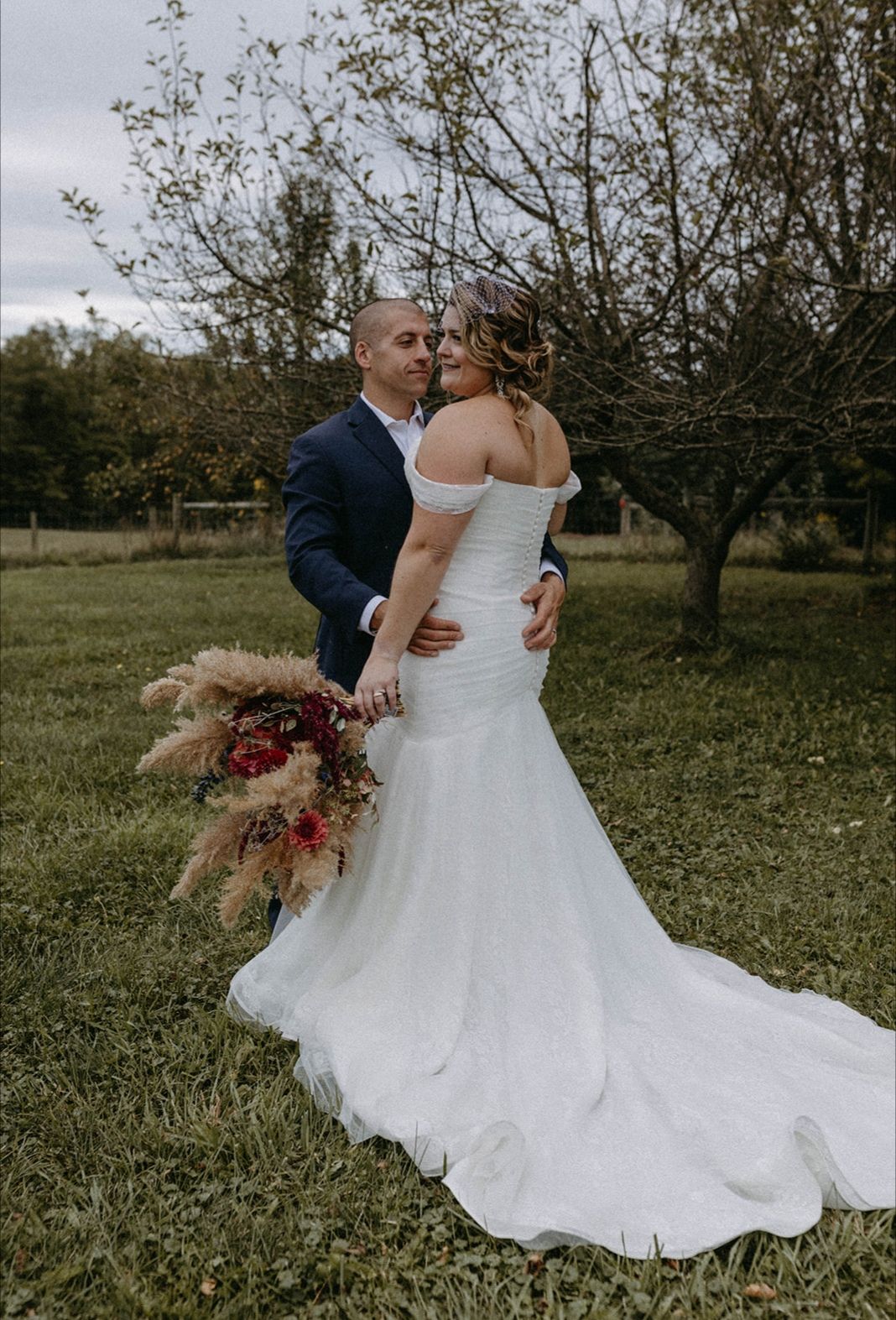 A bride and groom are posing for a picture in a field.