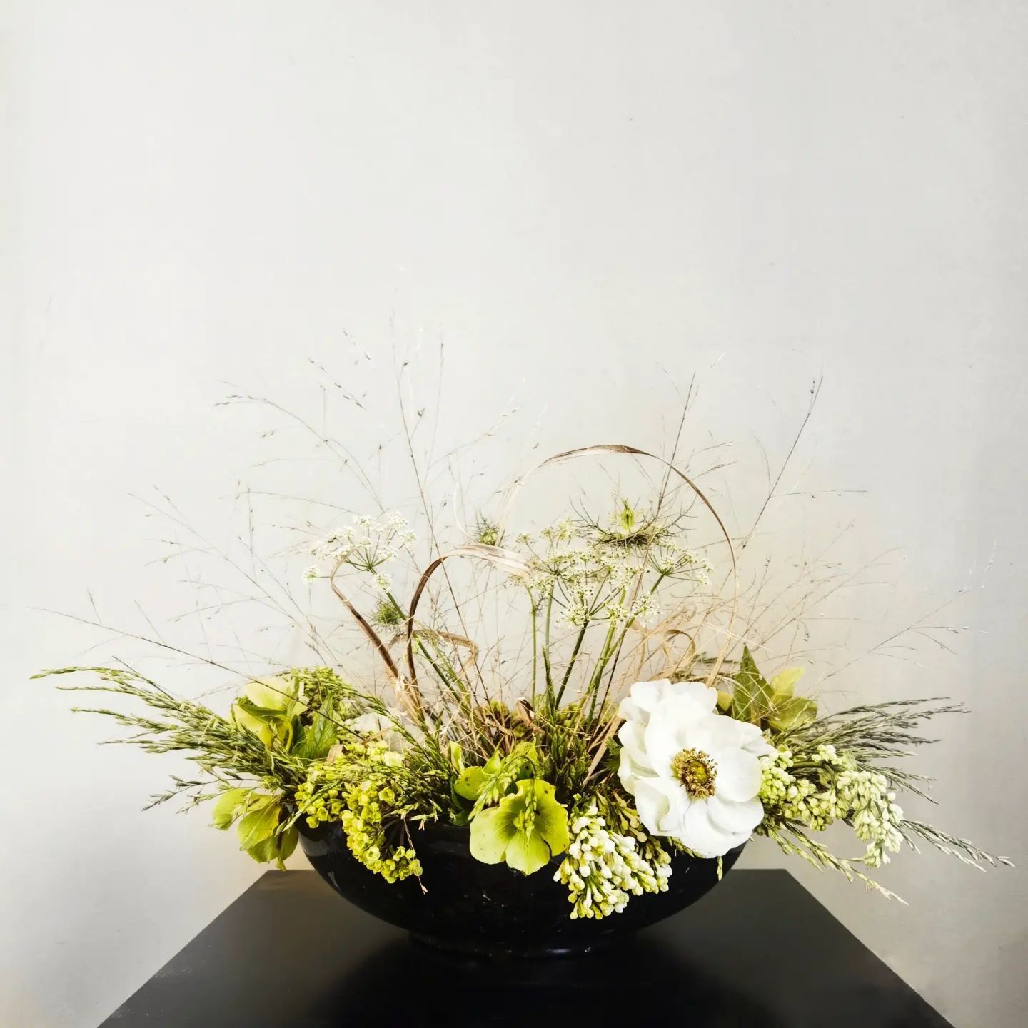 A black bowl filled with green and white flowers