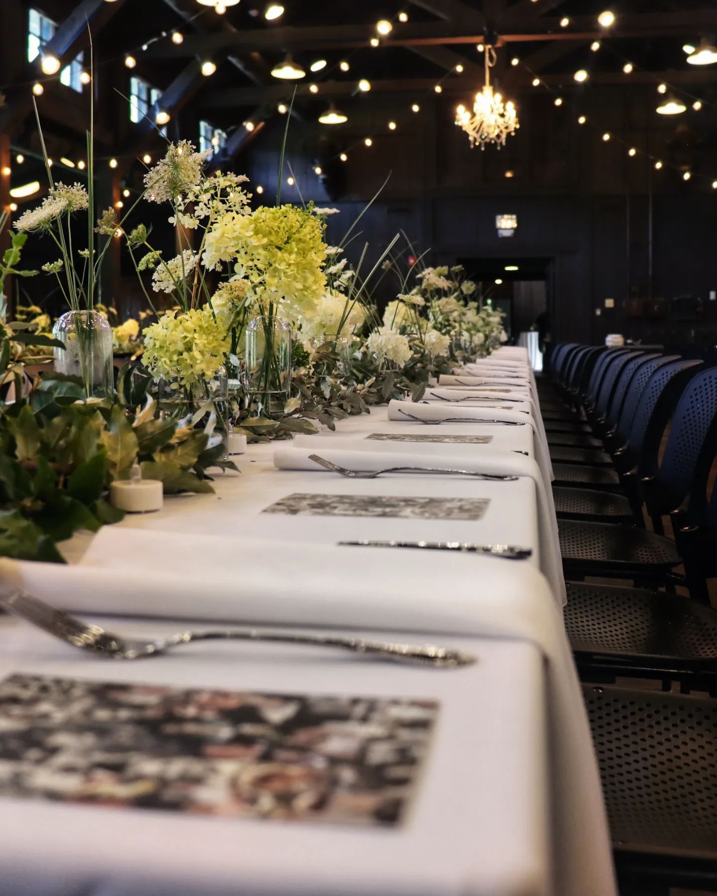 A long table with flowers on it in a dark room