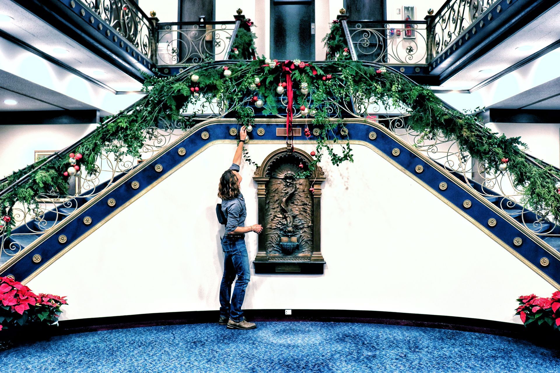 A woman is standing in front of a staircase decorated for christmas.