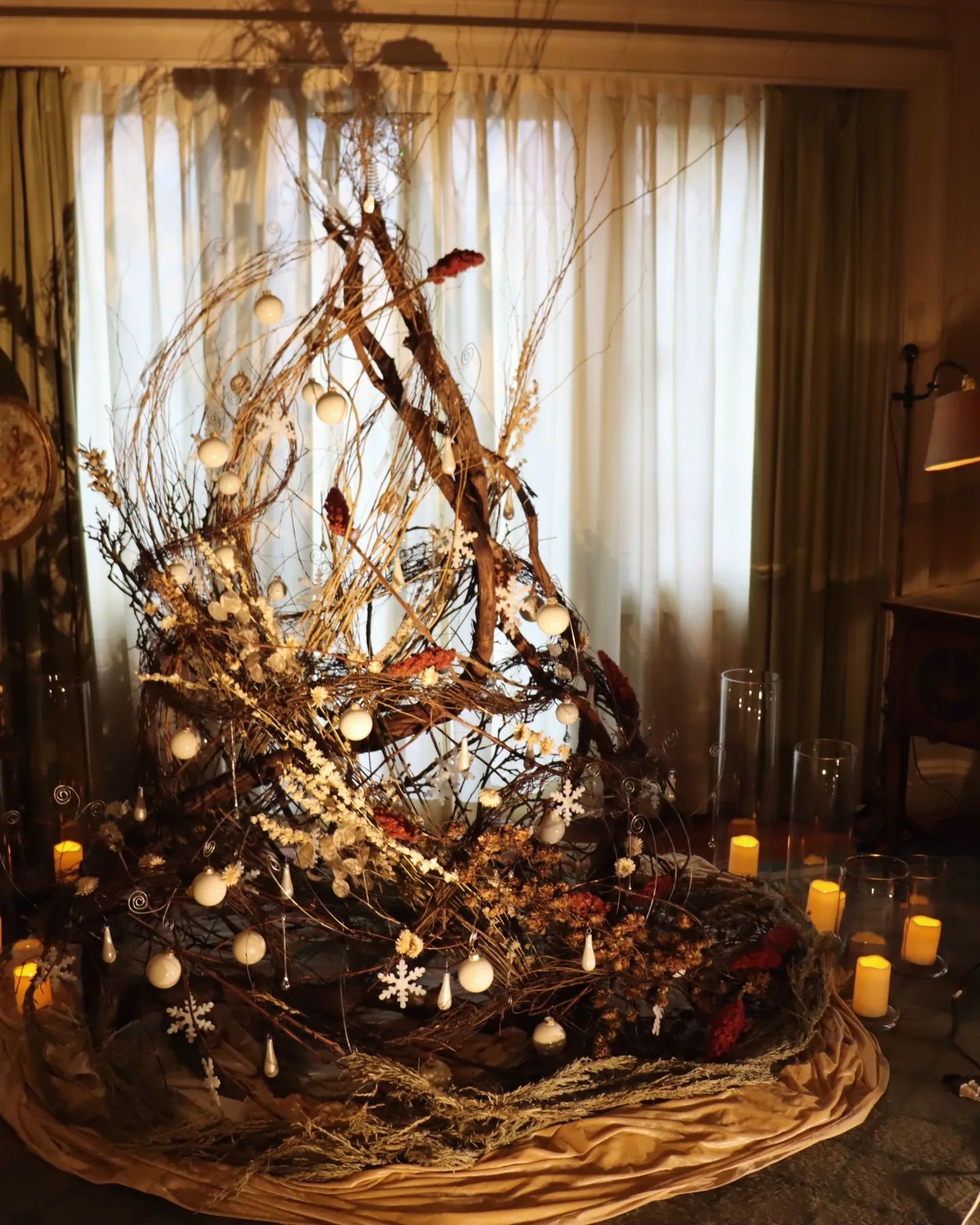 A christmas tree made of branches and candles in a living room
