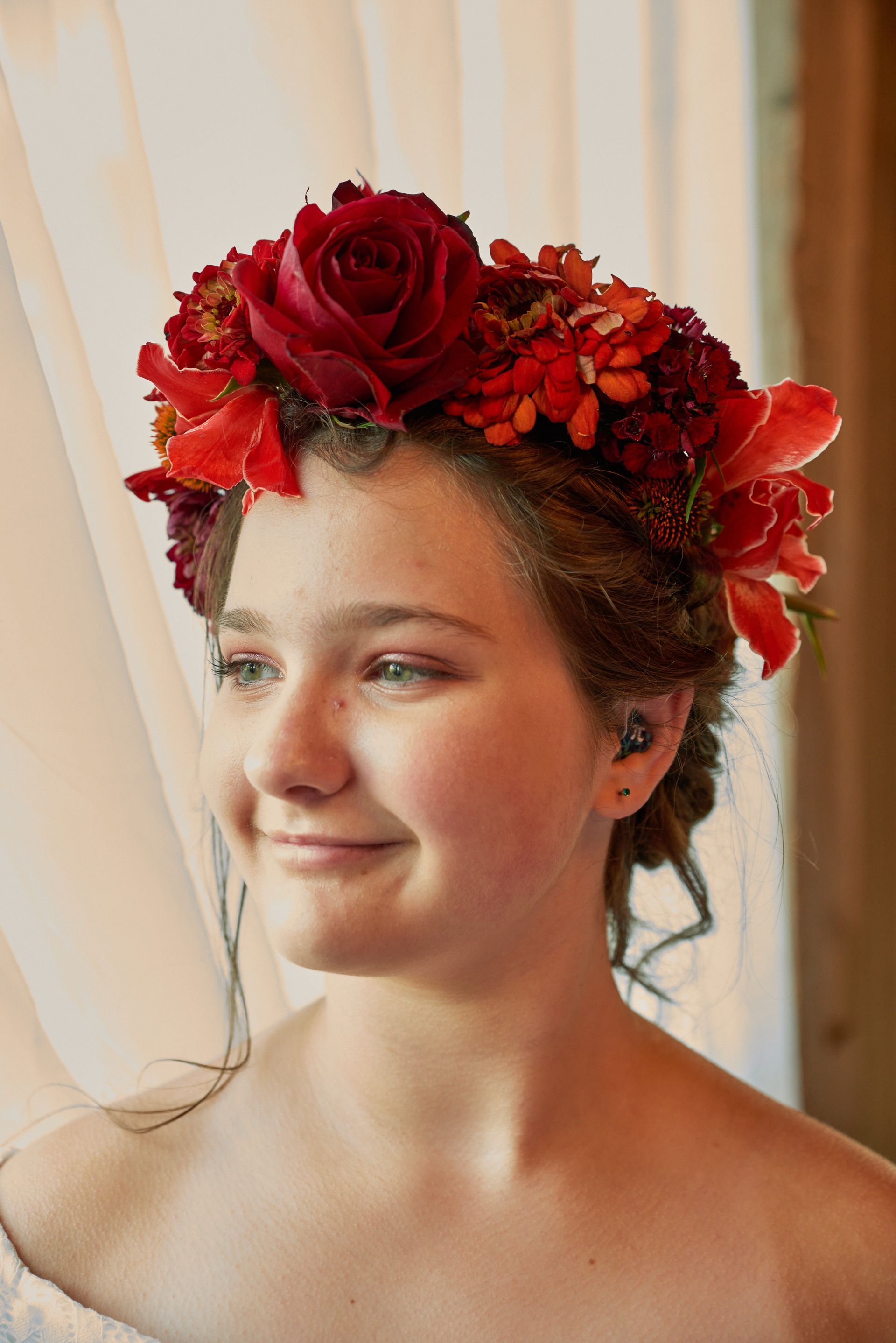 A woman wearing a crown of red flowers in her hair.