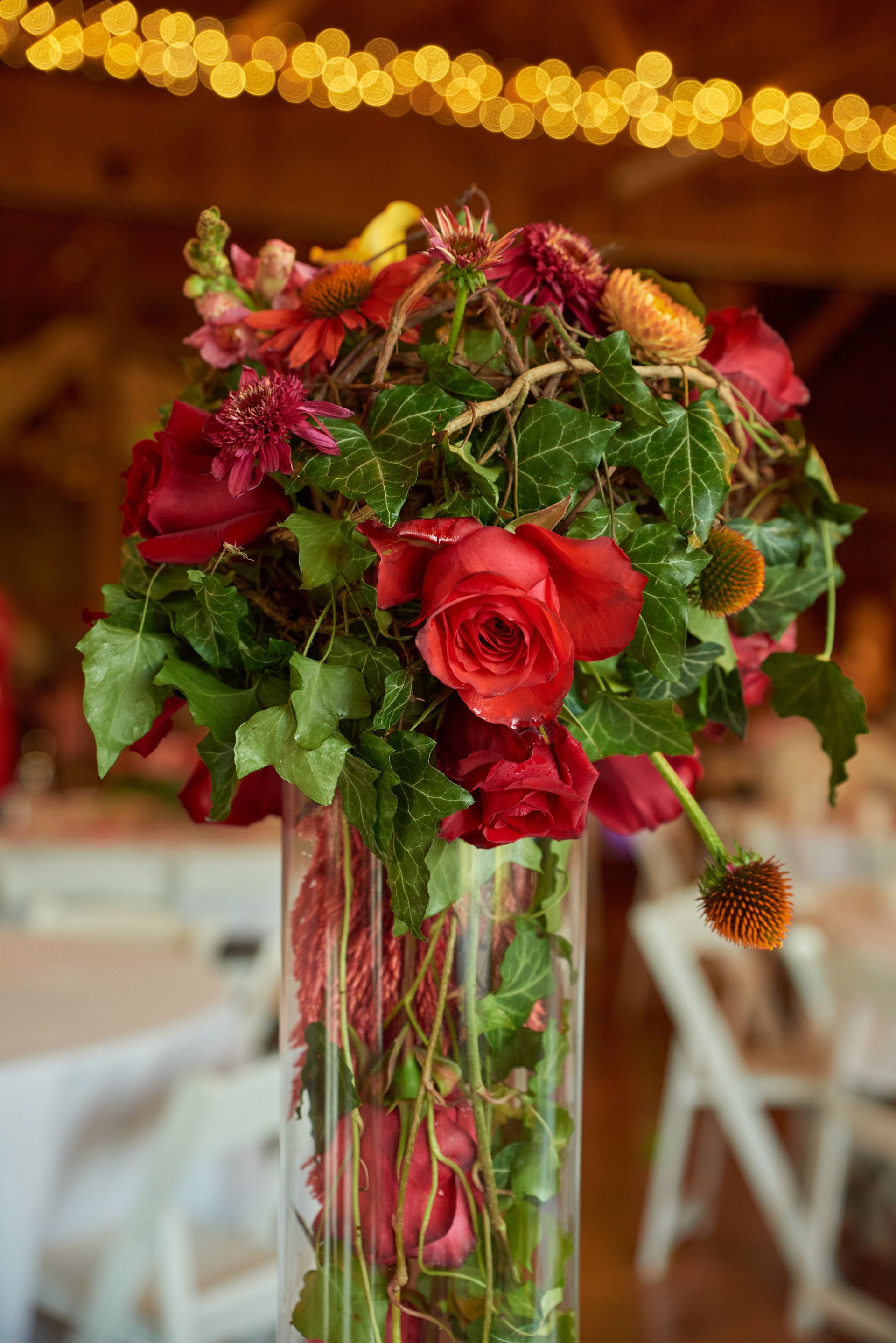 A vase filled with red roses and greenery is sitting on a table.