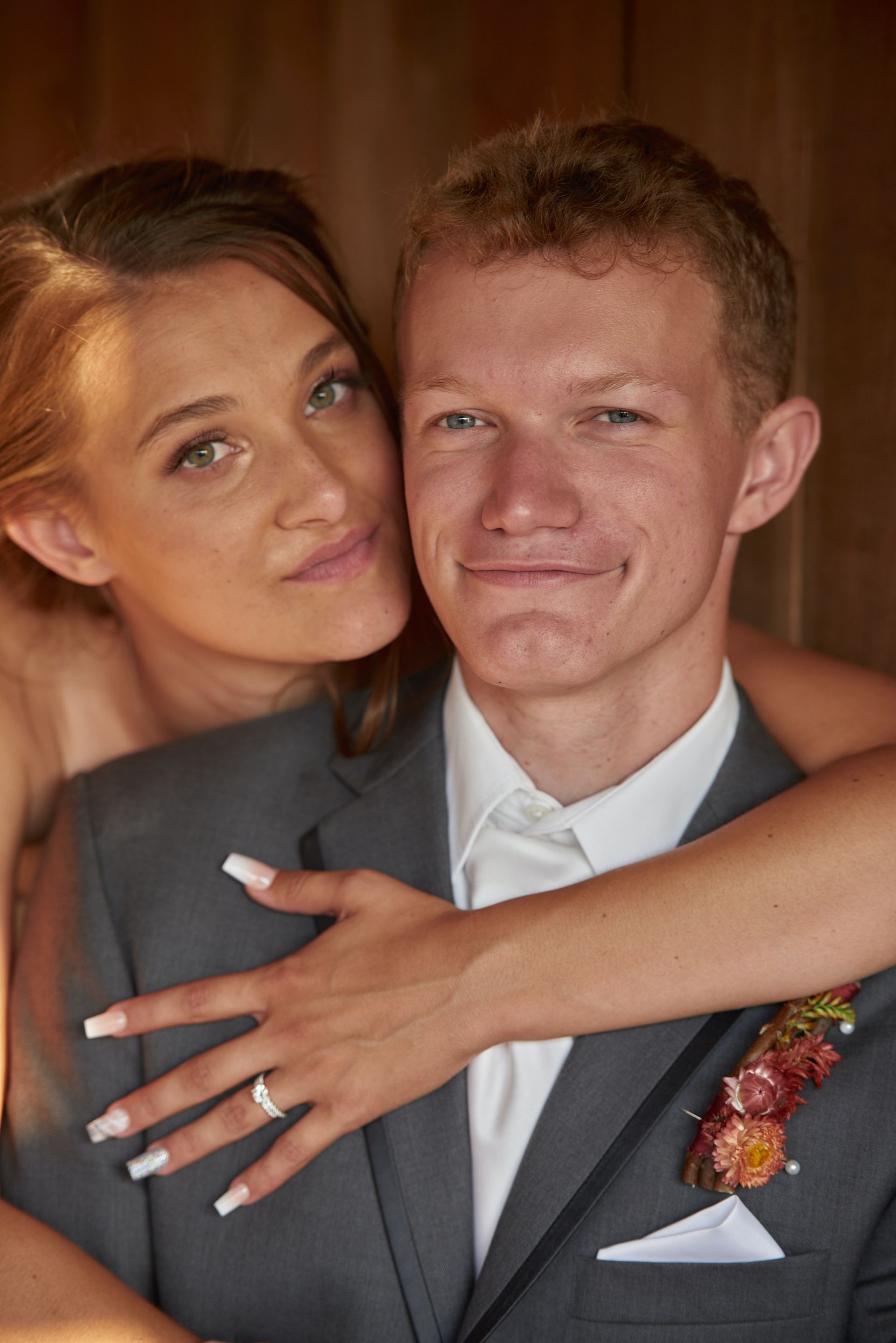 A bride and groom are posing for a picture and the bride is hugging the groom.