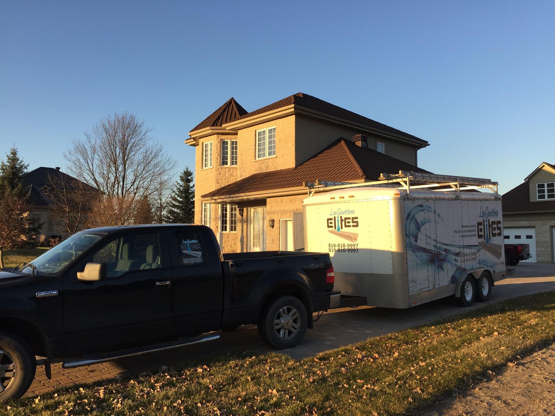 Un camion tire une remorque devant une maison.