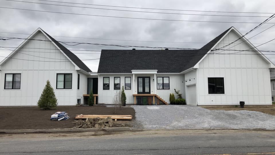 Une maison blanche avec un toit noir est en construction