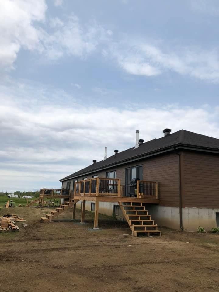 Une maison avec une terrasse en bois et des escaliers devant.