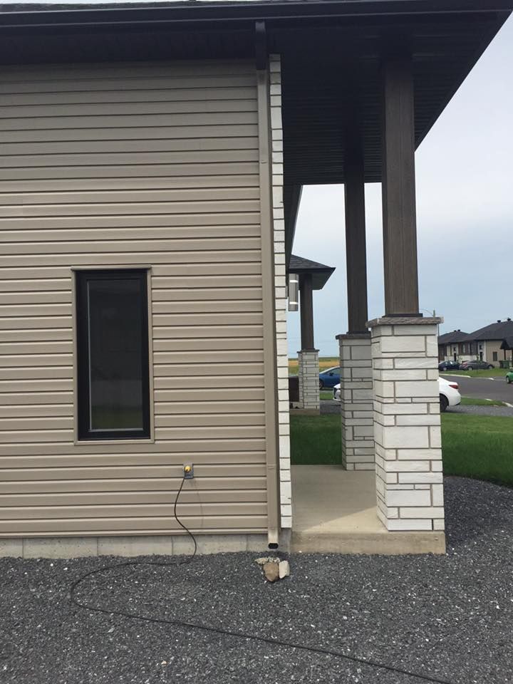 Le côté d'une maison avec un porche et une fenêtre