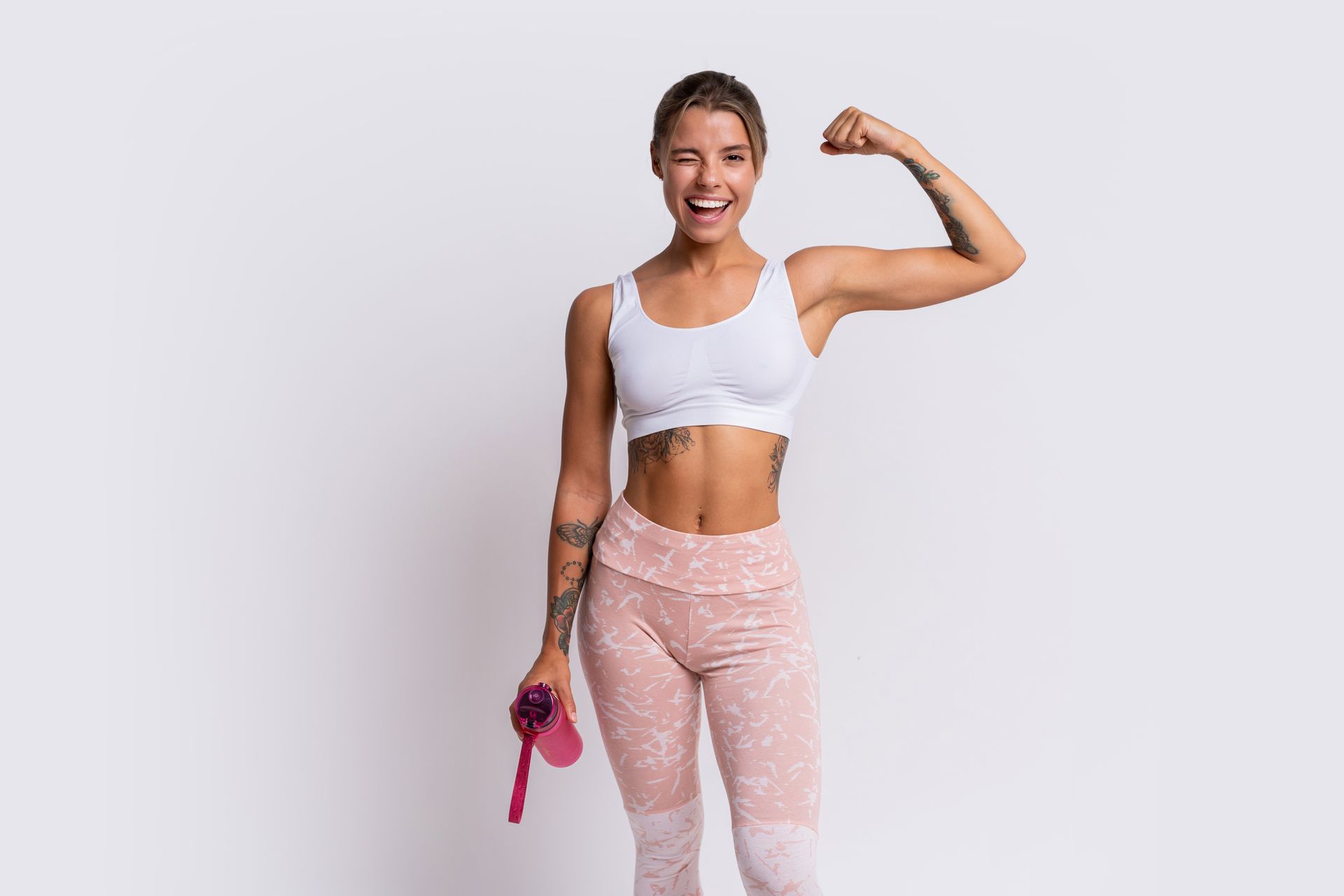 A woman is flexing her muscles while holding a water bottle.