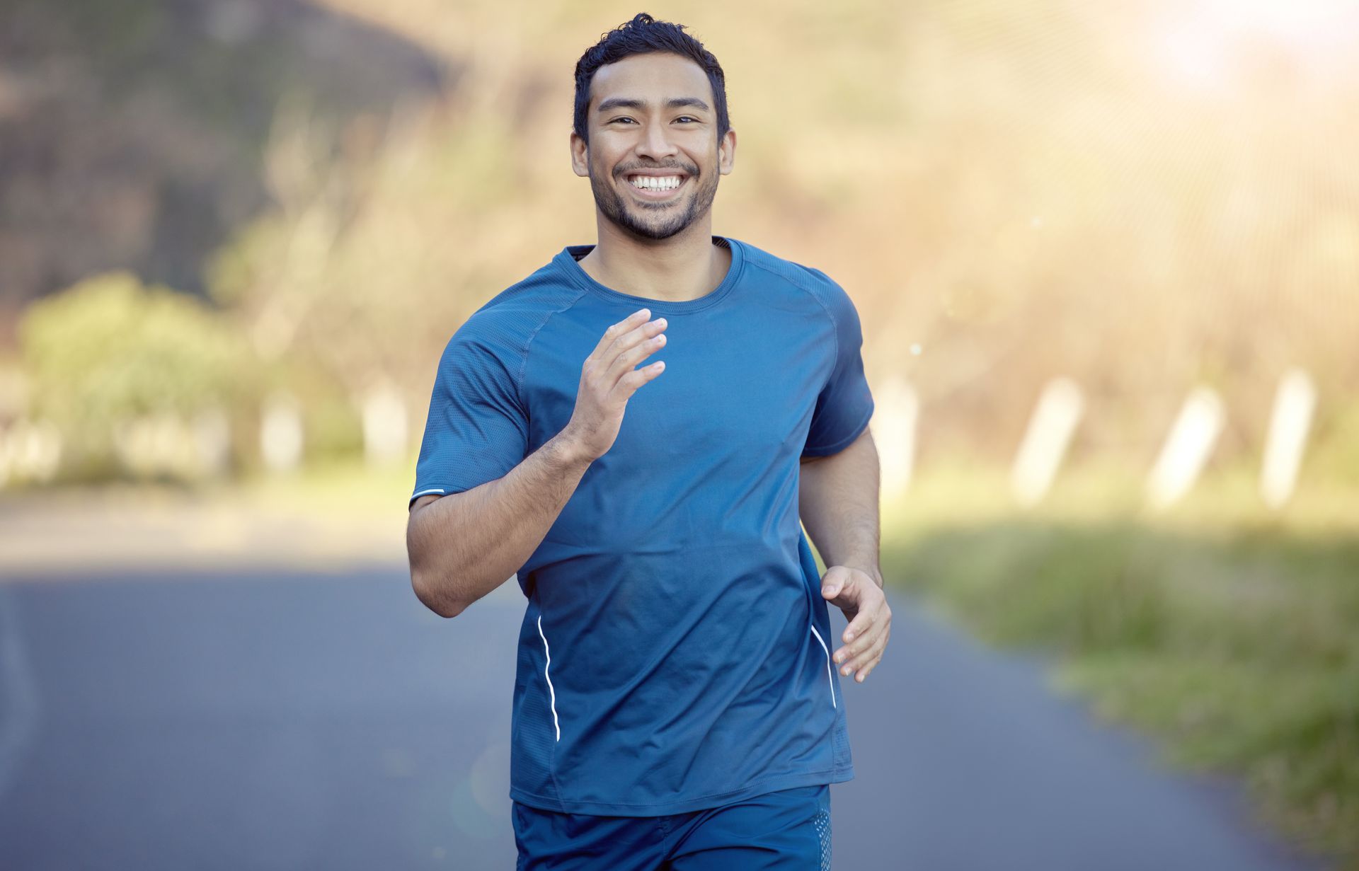 A man is smiling while running down a road.