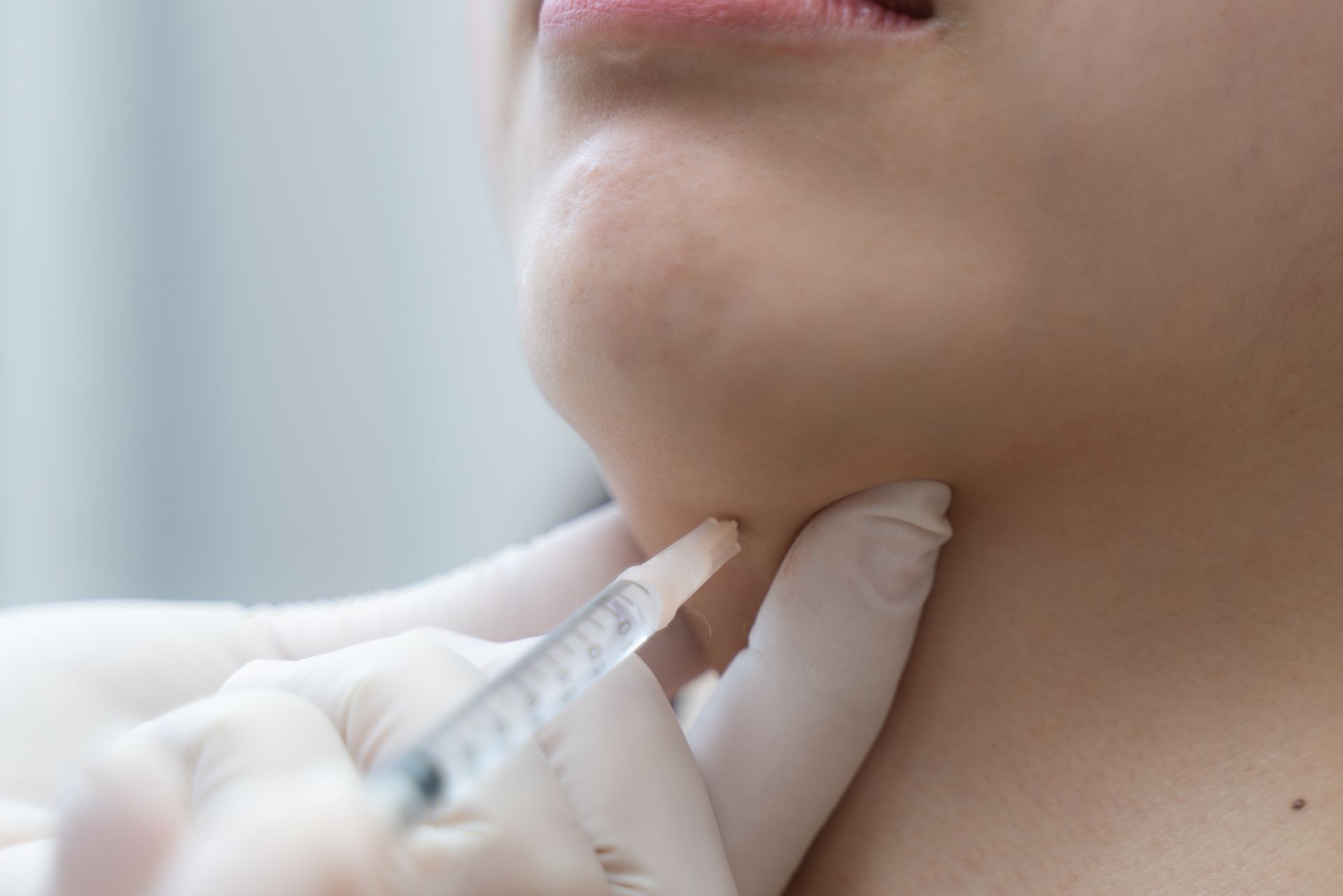 A woman is getting an injection in his neck by a doctor.