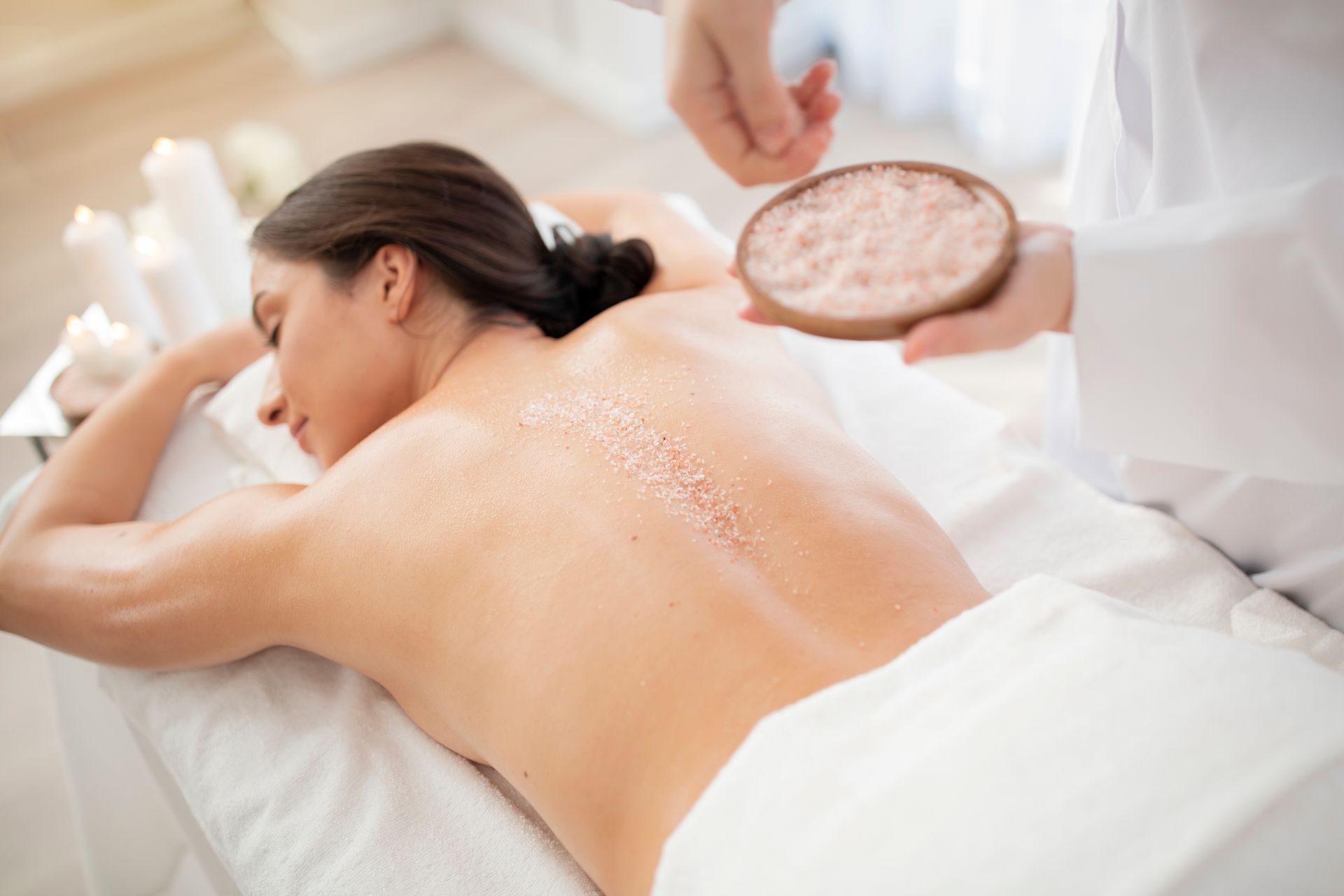 Woman receiving a salt scrub on her back at a spa.