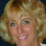 A close up of a woman 's face with blonde hair smiling.