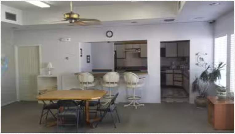 A room with a table and chairs and a ceiling fan
