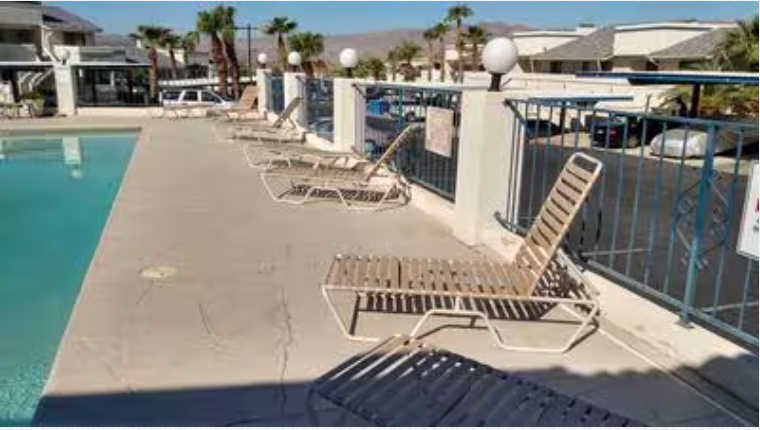 A row of lounge chairs are sitting next to a swimming pool.