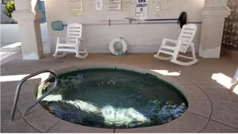 A round hot tub with rocking chairs and a life preserver in the background.