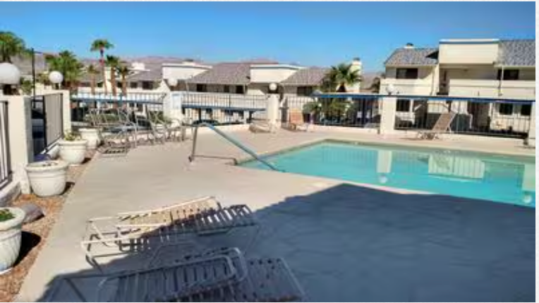 A large swimming pool is surrounded by chairs and potted plants.