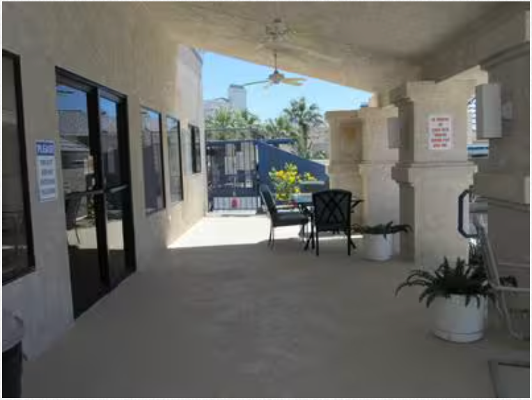 A covered porch with a table and chairs under a ceiling fan