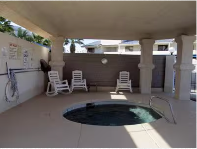 A hot tub surrounded by chairs under a covered area