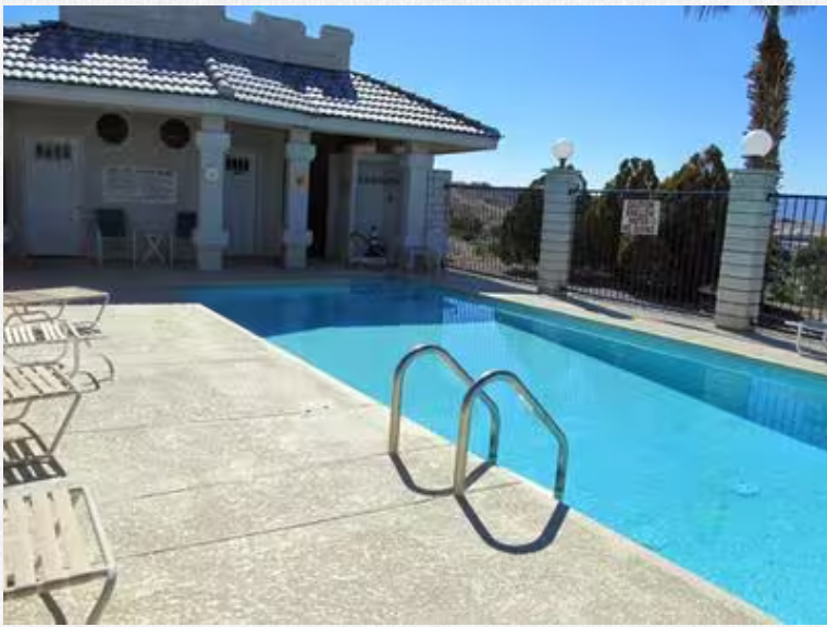 A large swimming pool with a house in the background