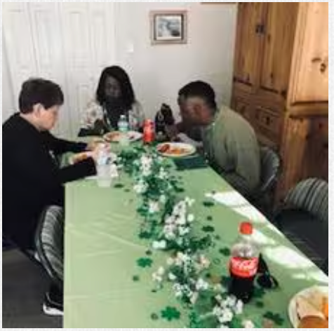 A group of people are sitting at a long table eating food.