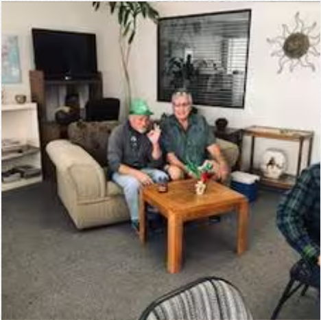 Two men are sitting on a couch and a table in a living room.