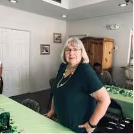 A woman is standing in front of a table in a room.