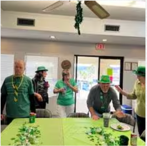 A group of people wearing green hats are standing around a table.
