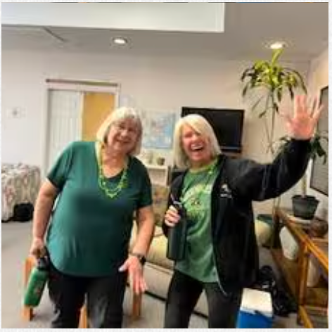 Two women are standing next to each other in a living room.