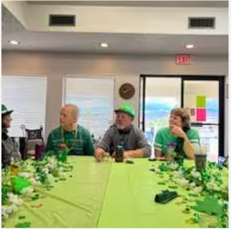 A group of people are sitting at a long table in a room.