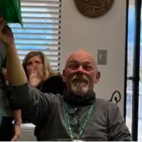 A man in a wheelchair is holding a green hat in his hand.