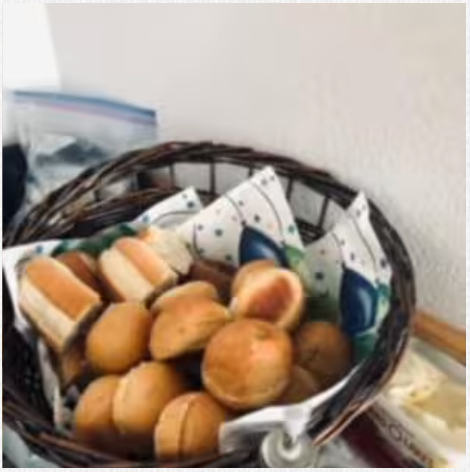 A basket filled with buns and rolls on a table.