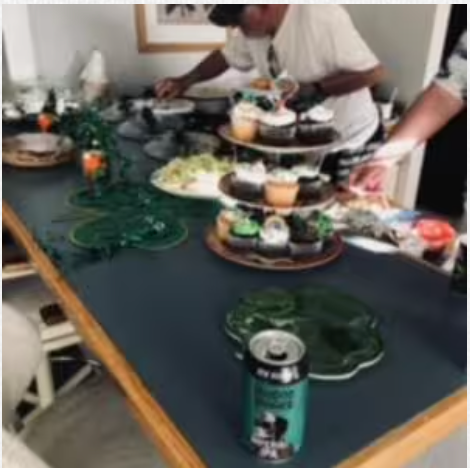 A man is standing at a table with plates of food on it.