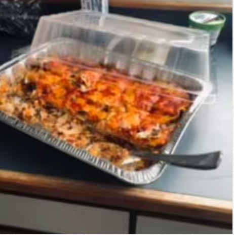 A tray of food with a plastic lid and a fork on a table.