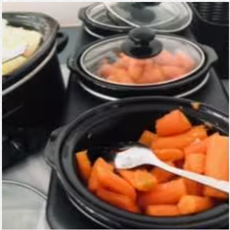 A crock pot filled with carrots and a spoon in it.