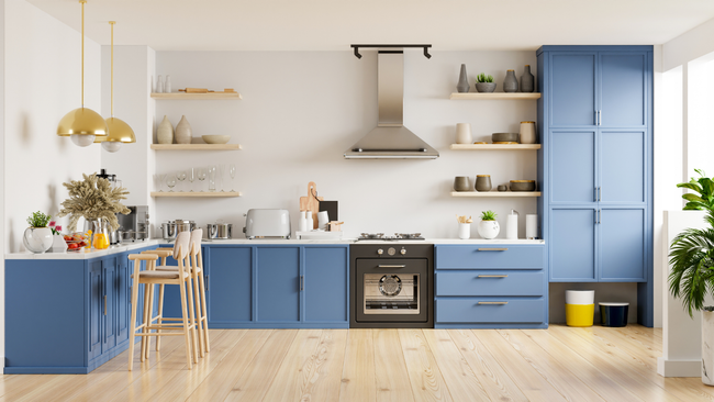 A kitchen with blue cabinets , wooden floors , a stove and a hood.