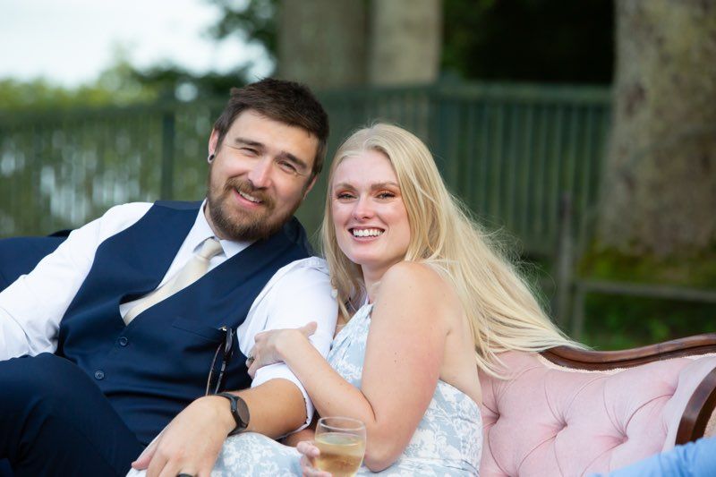 Football coach with arms crossed, standing on a football field. He wears a navy polo shirt and gray pants.