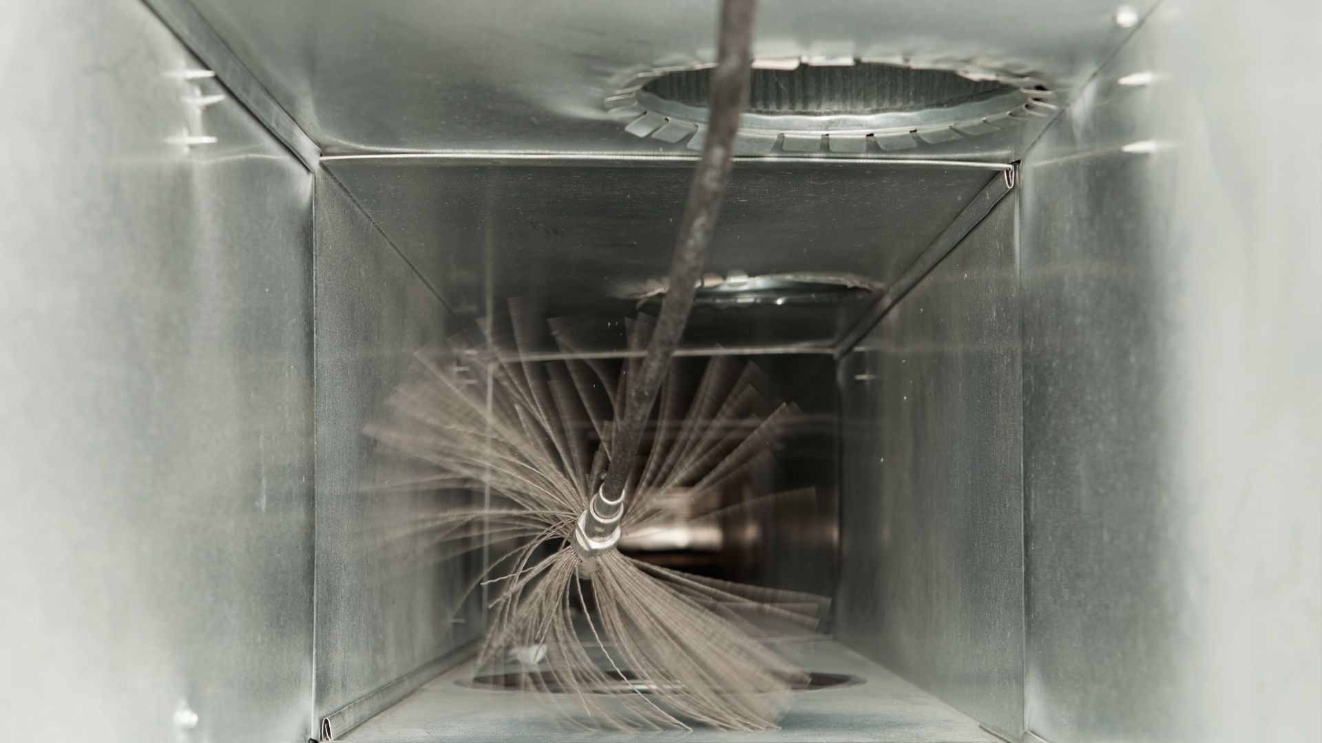 A duct with a brush in it is being cleaned.