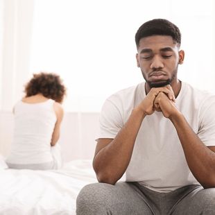 a man sits on a bed with his eyes closed