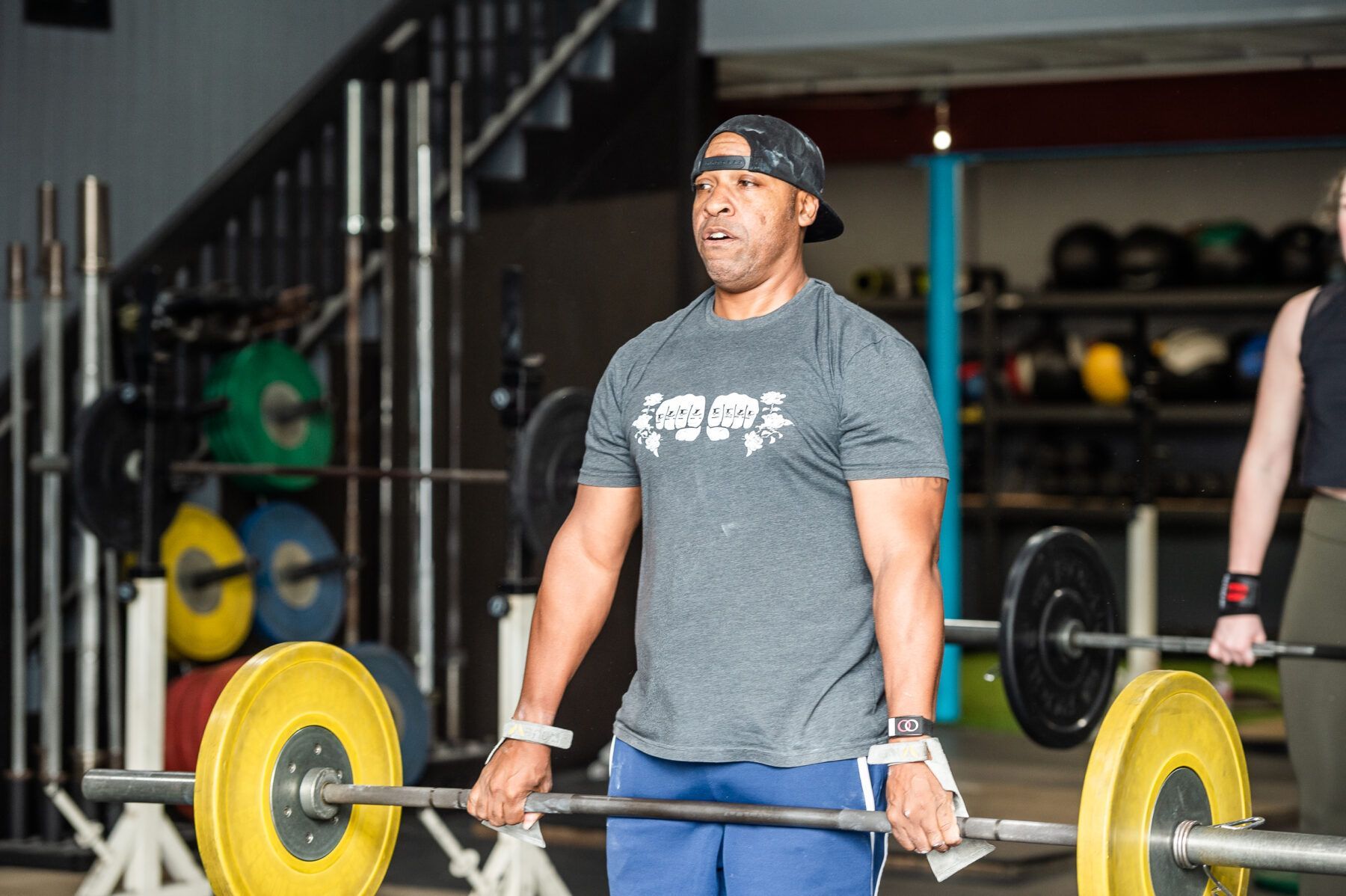 A man is lifting a barbell in a gym.