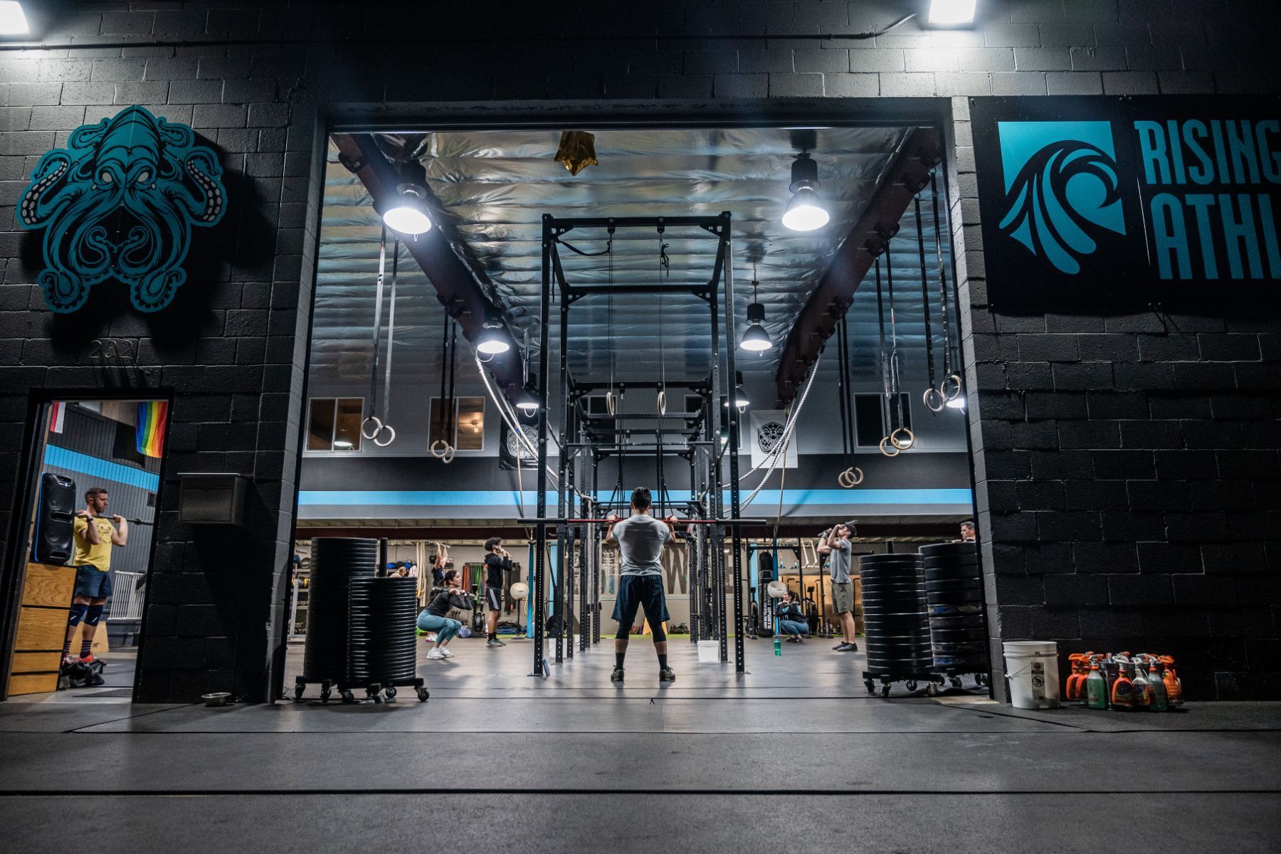 A man is doing squats in a gym with the door open.