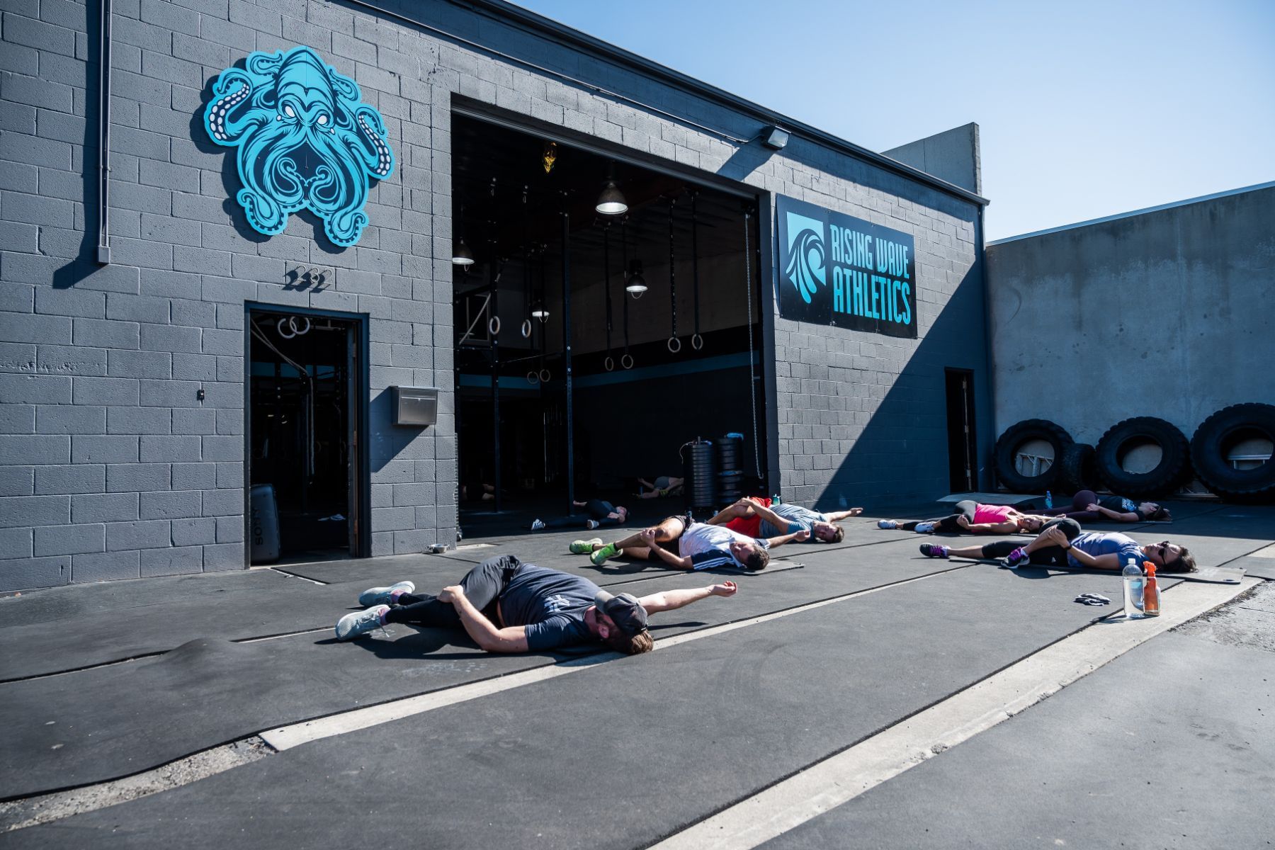 A group of people are laying on the ground in front of a building.