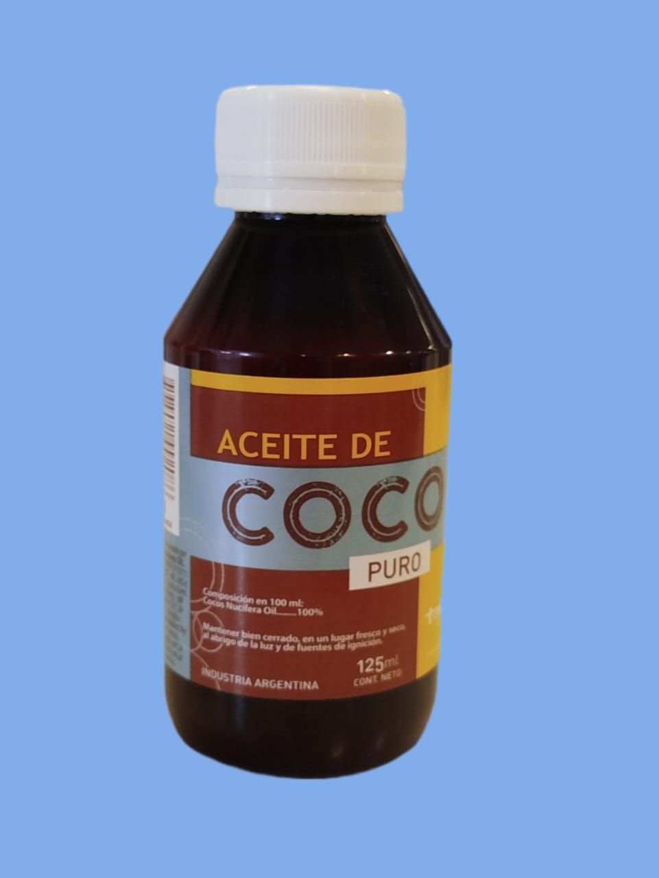 Una botella de líquido oscuro etiquetada "Aceite de Coco Puro" sobre un fondo azul.
