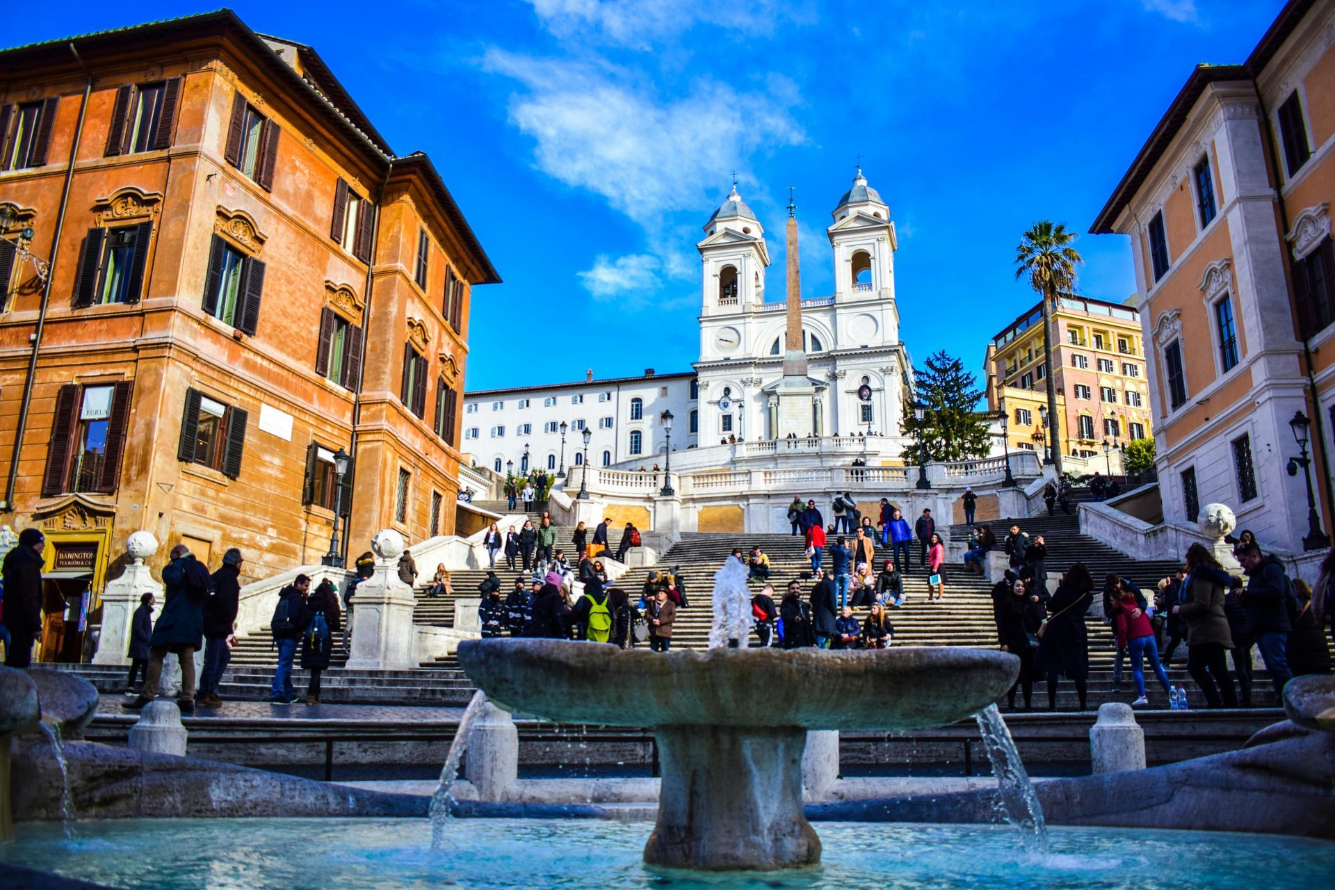 A group of people are standing around a fountain in front of a church.