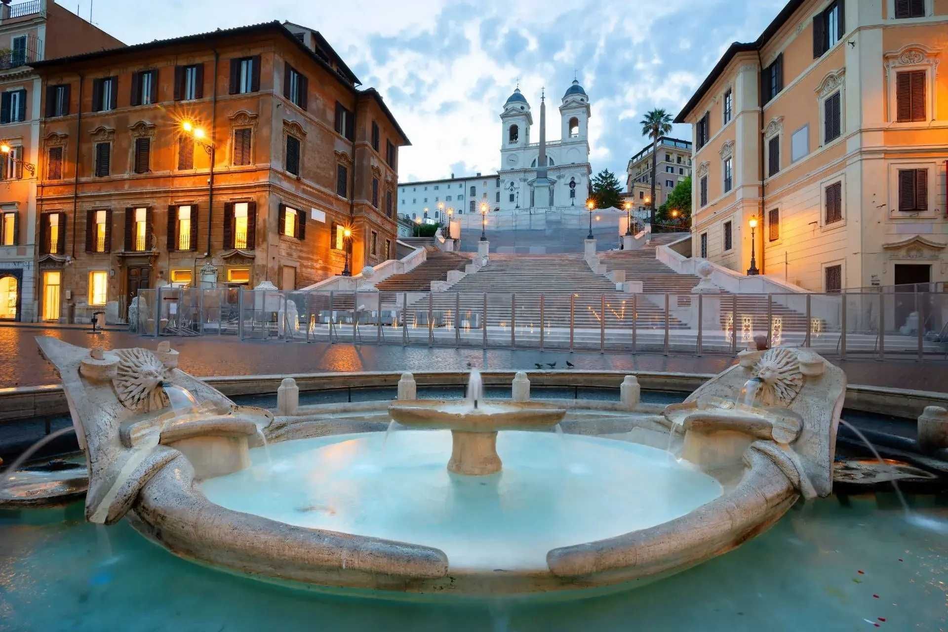 A fountain in the middle of a city with stairs in the background.