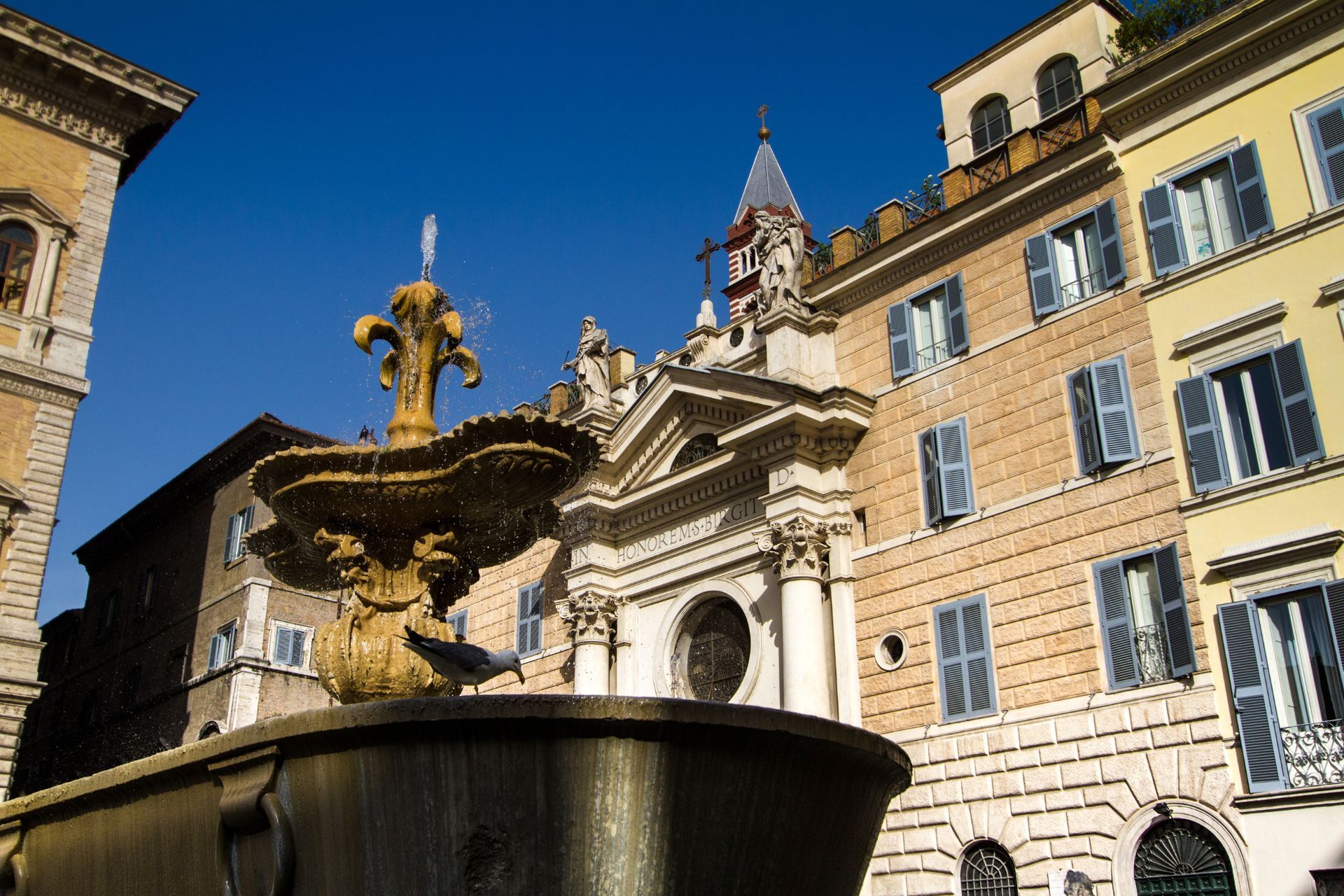 A fountain in front of a building with a clock tower
